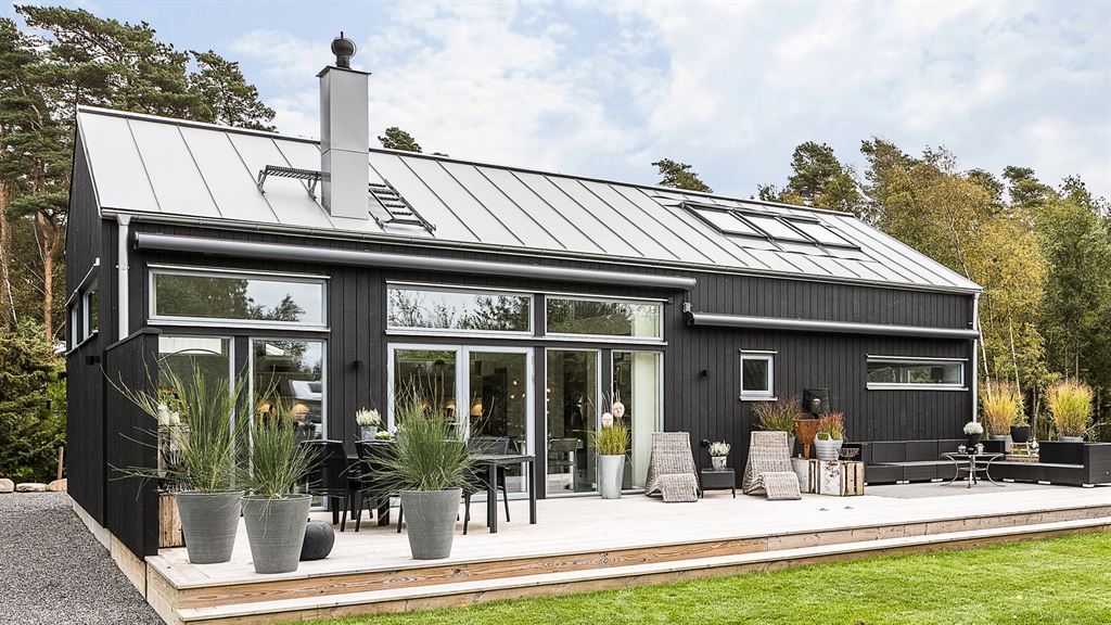 Exteriör bild av ett svart kundunikt fritidshus från Varbergshus