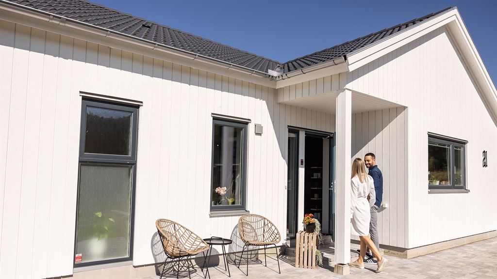 Visualisering av vitt enplanshus i lösvirke med grå detaljer