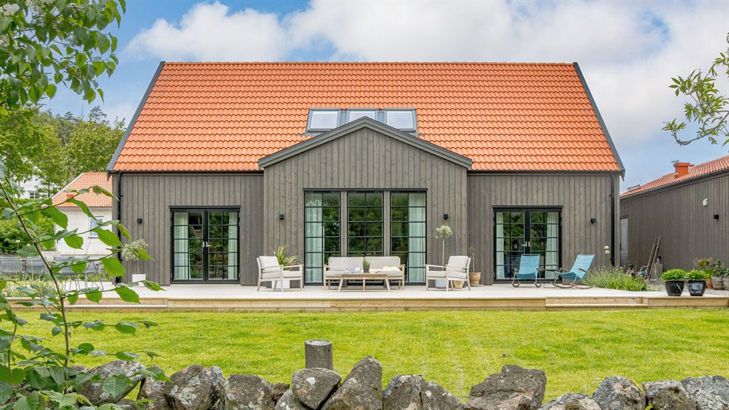 Visualisering av lösvirkeshus med svarta fönster och detaljer med orangea takpannor