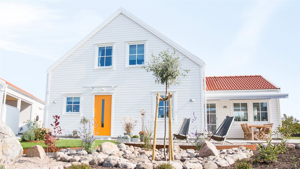 Vitt 2 plans hus i lösvirke med orange ytterdörr