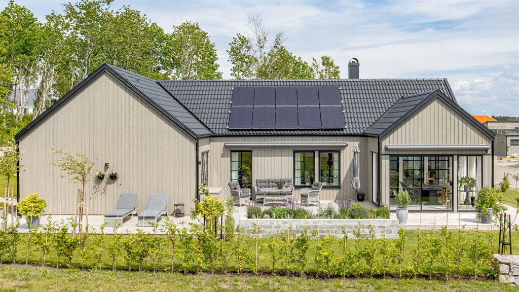 Visualisering av enplanshus med svarta detaljer och solceller på taket